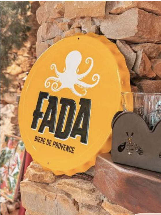 Plaque jaune FADA, bière de Provence, sur un mur en pierre