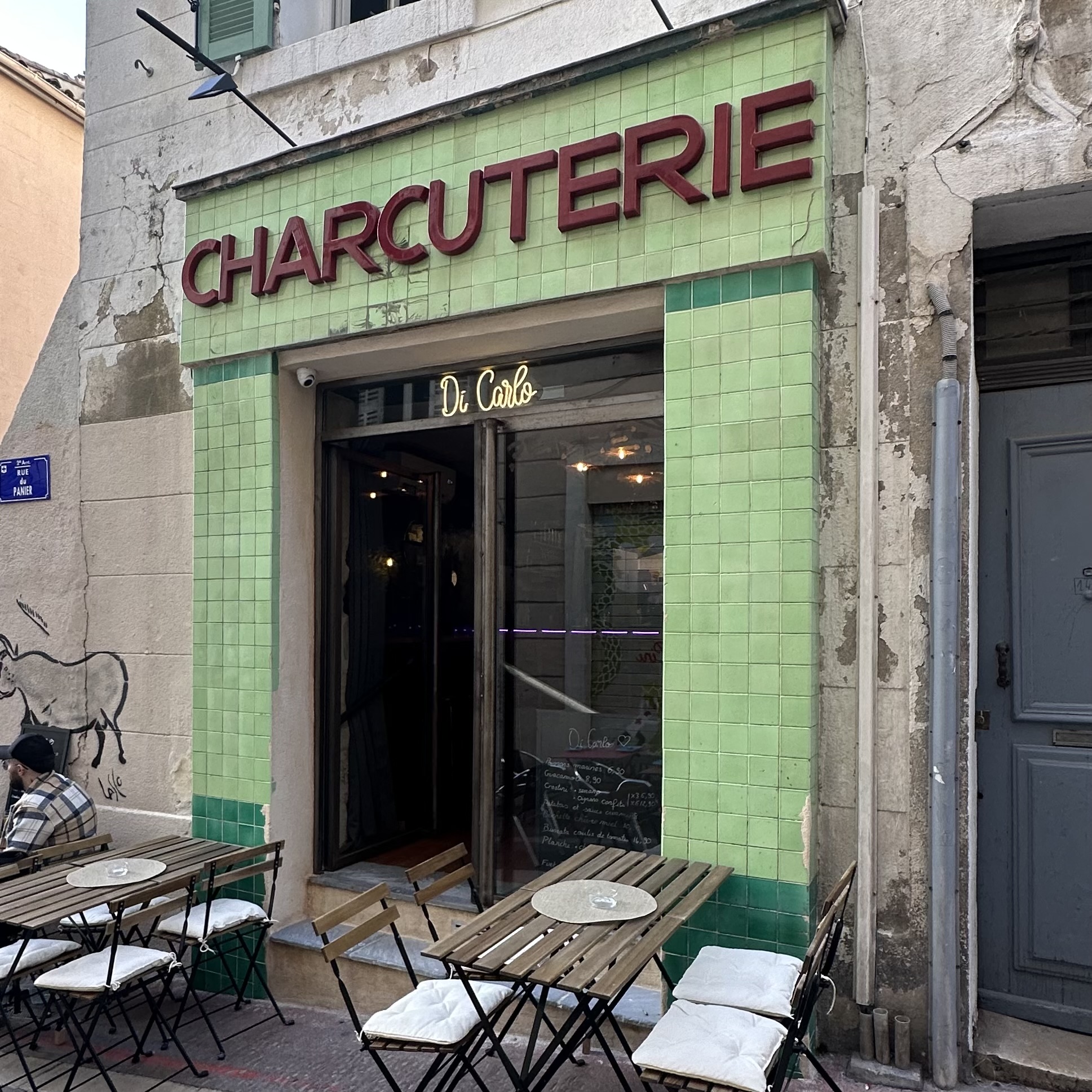 La façade actuelle du DiCarlo, avec les carreaux verts et l’enseigne Charcuterie visible dans la photographie originale